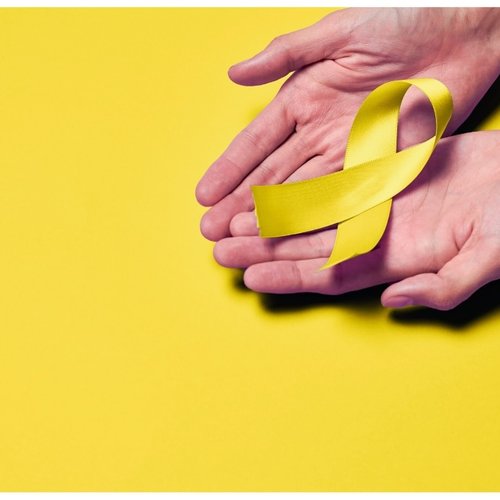 suicide ribbon in yellow being held in someone's hands