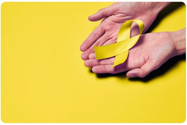 suicide ribbon in yellow being held in someone's hands